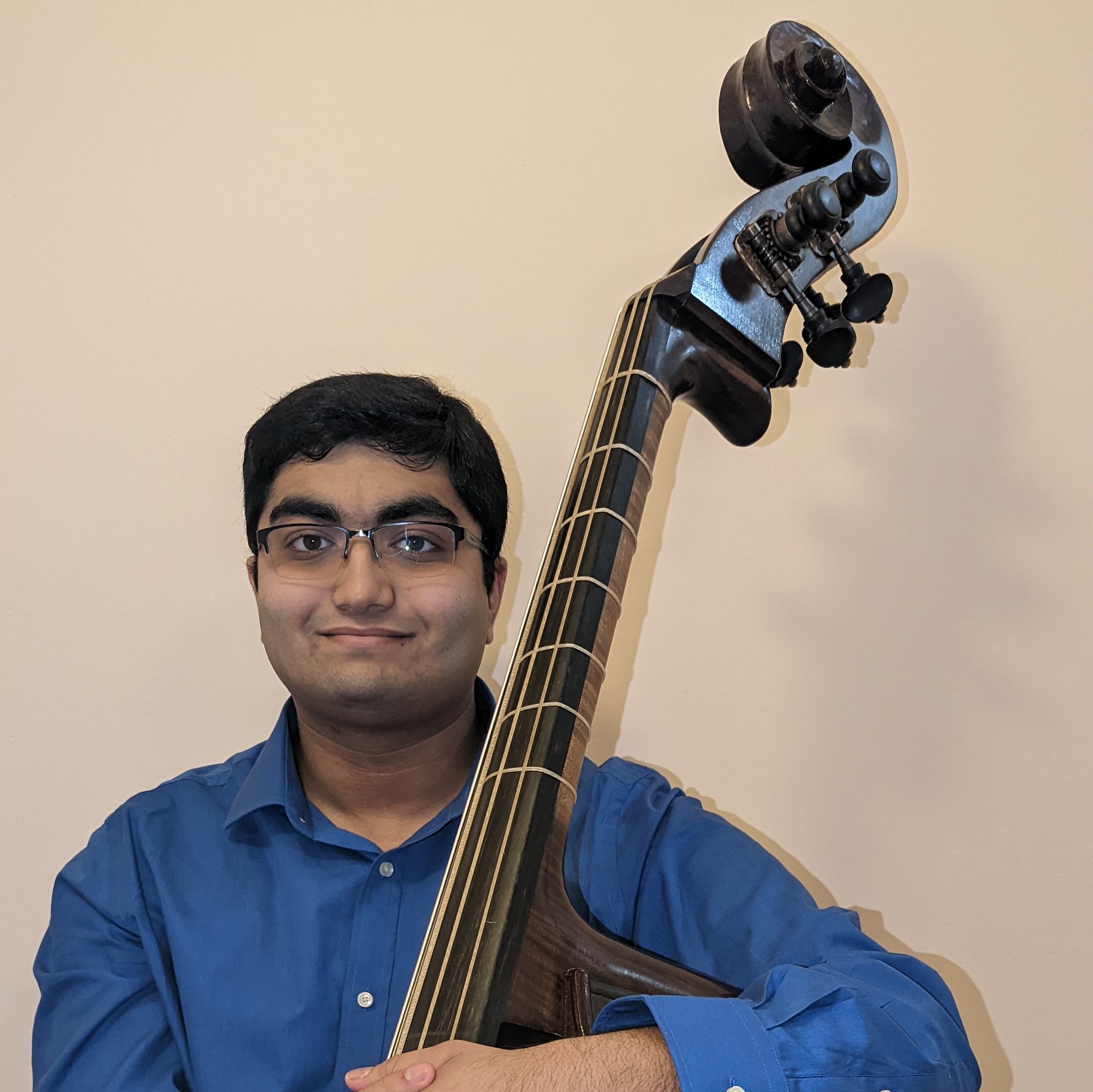 Shrish in a blue shirt, holding his Pacific Violone in Viennese tuning, Seth Kimmel Bass #72, made in 2022.